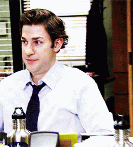 A Man In A Tie Sits At A Desk With A Water Bottle In Front Of Him GIF