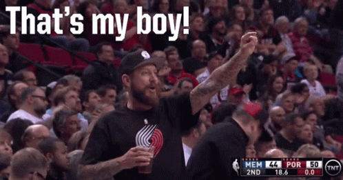 A Man In A Tnt Shirt Stands In Front Of A Crowd GIF