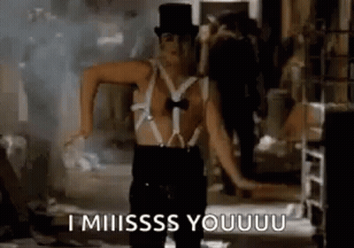 A Man In A Top Hat And Suspenders Is Dancing In A Dark Room . GIF