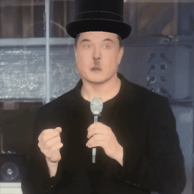 A Man In A Top Hat Holds A Microphone GIF
