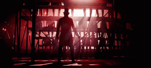 A Man In A Top Hat Is Dancing In A Dark Room With Red Lights . GIF