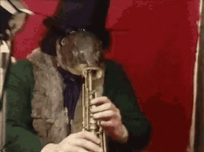 A Man In A Top Hat Is Playing A Trumpet In Front Of A Red Background . GIF