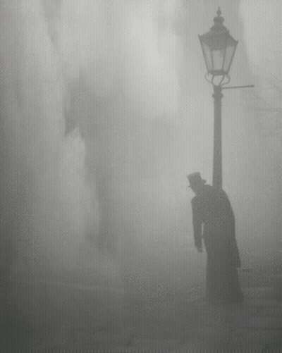 A Man In A Top Hat Is Standing Next To A Street Light GIF