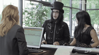 A Man In A Top Hat Is Talking To Two Women In Front Of A Computer Screen That Says Portlandia On It GIF