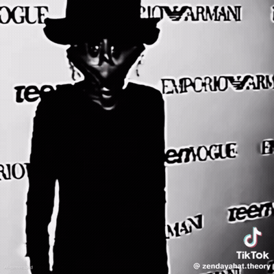 A Man In A Top Hat Stands In Front Of A Wall That Says Vogue GIF