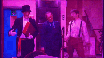 A Man In A Top Hat Stands Next To Two Other Men In Suits GIF