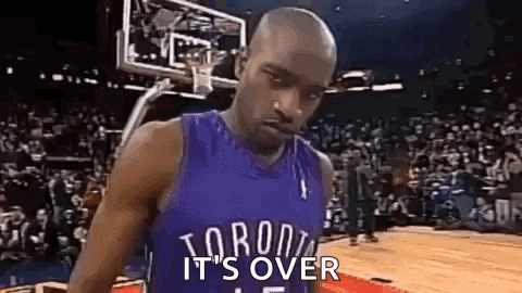 A Man In A Toronto Raptors Jersey Is Standing On A Basketball Court With A Basketball Hoop In The Background . GIF