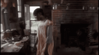 A Man In A Towel Is Standing In A Room With A Fireplace . GIF