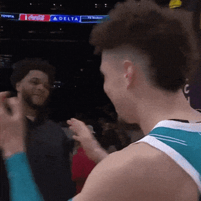 A Man In A Toyota Jersey Talks To Another Man In Front Of A Delta Sign GIF
