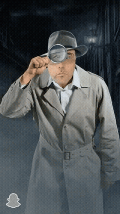 A Man In A Trench Coat And Hat Looking Through A Magnifying Glass GIF