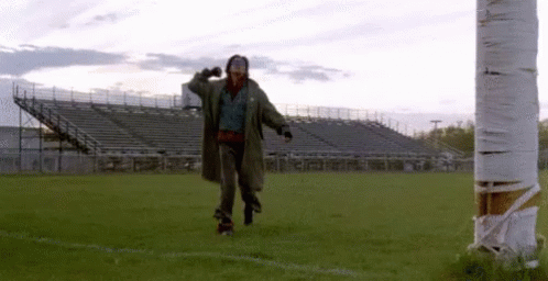 A Man In A Trench Coat Is Rollerblading On A Field . GIF