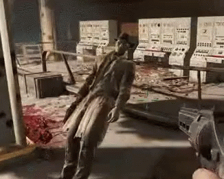 A Man In A Trench Coat Is Standing In A Room With A Gun In His Hand . GIF