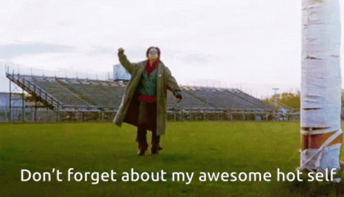 A Man In A Trench Coat Stands In A Field With The Words " Don 'T Forget About My Awesome Hot Self " GIF