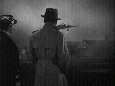 A Man In A Trench Coat Stands In Front Of A Plane That Says Jet GIF