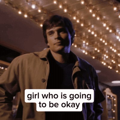 A Man In A Trench Coat Stands In Front Of A Sign That Says Girl Who Is Going To Be Ok GIF