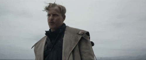 A Man In A Trench Coat With A Badge On His Shoulder GIF