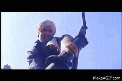 A Man In A Turban Is Holding A Large Sword In His Hand . GIF