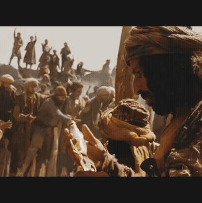 A Man In A Turban Is Holding Something In Front Of A Crowd Of People GIF