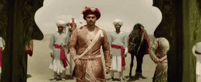 A Man In A Turban Is Standing In Front Of A Group Of Men And A Horse GIF