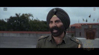 A Man In A Turban With A Beard Is Standing In Front Of A Building GIF
