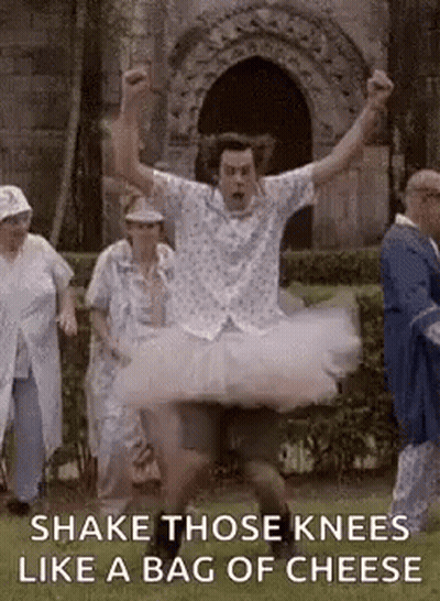 A Man In A Tutu Is Dancing In Front Of A Group Of People In A Park . GIF