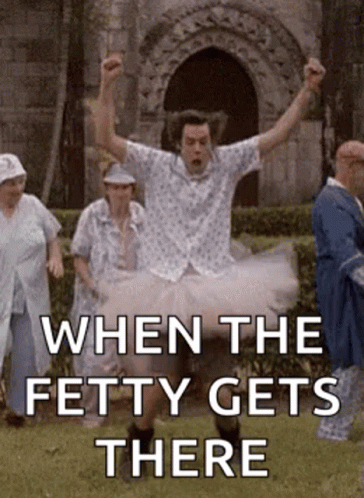 A Man In A Tutu Is Jumping In The Air While A Group Of People Are Standing Behind Him . GIF