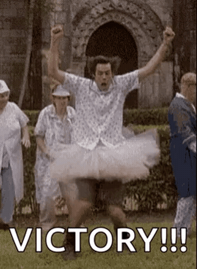 A Man In A Tutu Is Jumping In The Air With His Arms In The Air In Front Of A Group Of People . GIF