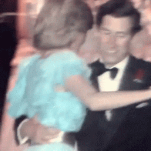 A Man In A Tuxedo And A Woman In A Blue Dress Are Dancing . GIF