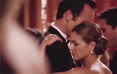 A Man In A Tuxedo And A Woman In A White Dress Are Dancing Together . GIF