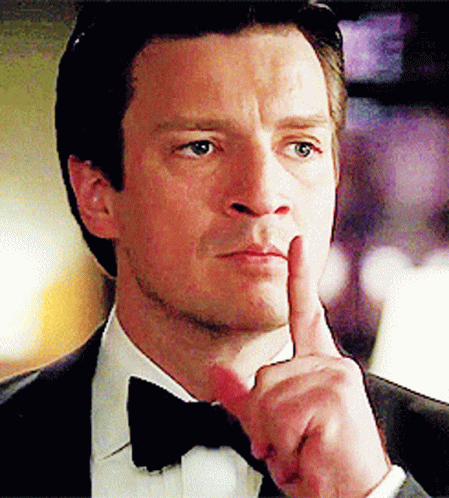 A Man In A Tuxedo And Bow Tie Holds His Finger To His Chin GIF