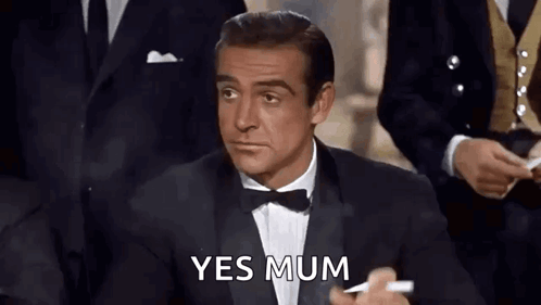 A Man In A Tuxedo And Bow Tie Is Holding A Cigarette And Says Yes Mum . GIF