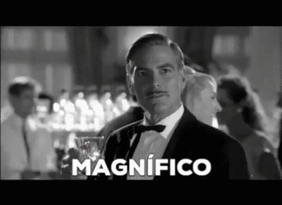 A Man In A Tuxedo And Bow Tie Is Holding A Glass Of Wine And Says Magnifico In Spanish . GIF