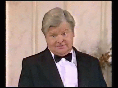 A Man In A Tuxedo And Bow Tie Is Making A Face . GIF