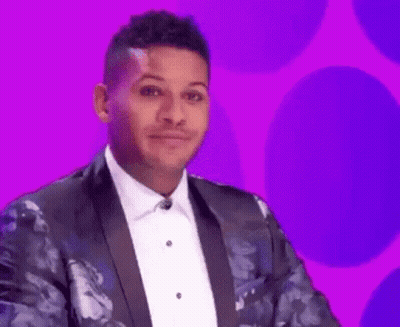 A Man In A Tuxedo And Bow Tie Is Making A Funny Face On A Purple Background . GIF