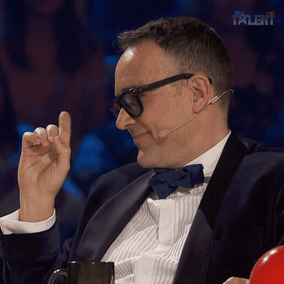 A Man In A Tuxedo And Bow Tie Is Sitting In Front Of A Sign That Says " My Talent " GIF