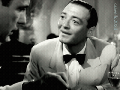 A Man In A Tuxedo And Bow Tie Is Smiling In A Black And White Photo GIF
