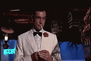 A Man In A Tuxedo And Bow Tie Is Smoking A Cigarette GIF