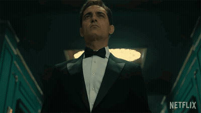 A Man In A Tuxedo And Bow Tie Is Standing In A Hallway With A Netflix Logo In The Background GIF