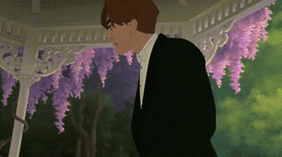 A Man In A Tuxedo And Bow Tie Is Standing In Front Of A Gazebo With Purple Flowers . GIF