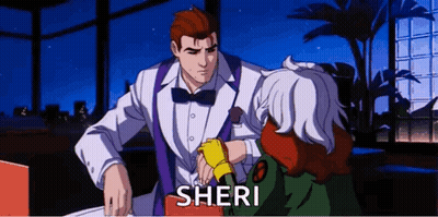 A Man In A Tuxedo And Bow Tie Is Talking To A Woman In A Green Jacket Named Sheri . GIF