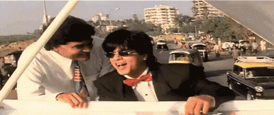 A Man In A Tuxedo And Bow Tie Is Talking To Another Man GIF