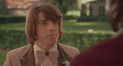 A Man In A Tuxedo And Bow Tie Is Talking To Another Man In A Park . GIF