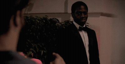 A Man In A Tuxedo And Bow Tie Is Talking To Another Man GIF