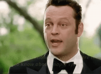 A Man In A Tuxedo And Bow Tie Is Talking To Another Man . GIF