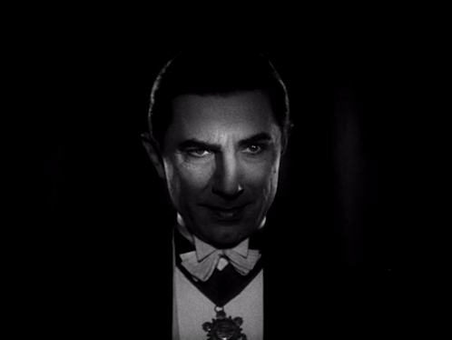 A Man In A Tuxedo And Bow Tie Looks At The Camera GIF