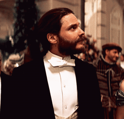 A Man In A Tuxedo And Bow Tie Looks To His Left GIF