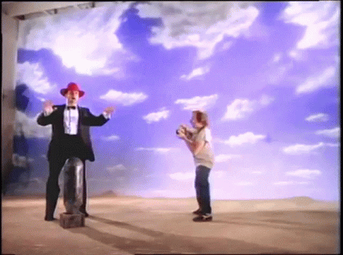 A Man In A Tuxedo And Red Hat Is Standing Next To A Boy In A White Shirt GIF