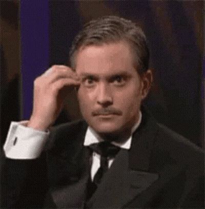 A Man In A Tuxedo And Tie Is Scratching His Forehead . GIF