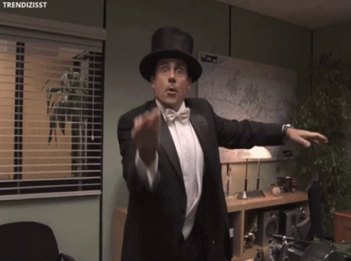 A Man In A Tuxedo And Top Hat Is Pointing A Gun With The Hashtag Trendizisst Below Him GIF