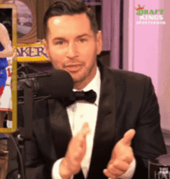 A Man In A Tuxedo Applauds In Front Of A Microphone GIF